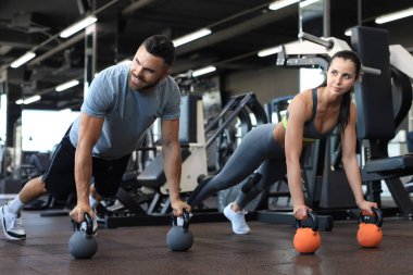 Spor salonunda şınav çeken kadın ve erkek.