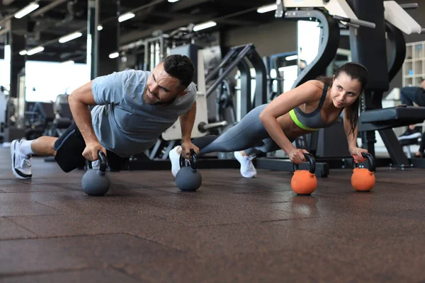 Spor salonunda şınav çeken kadın ve erkek.