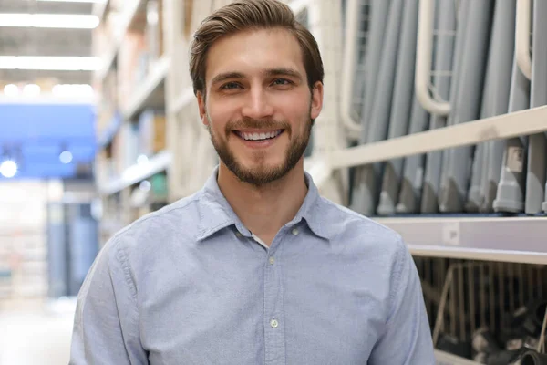 Retrato de un joven trabajador de almacén sonriente que trabaja en efectivo y lleva una tienda al por mayor . — Foto de Stock