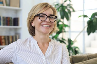 Sarışın, orta yaşlı, güzel bir kadın koltukta dinleniyor.