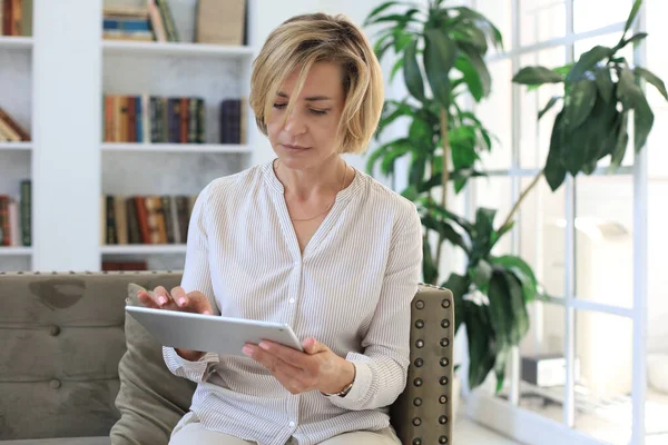 Glada Medelålders Kvinna Sitter Soffan Med Hjälp Dator Tablet Apps — Stockfoto