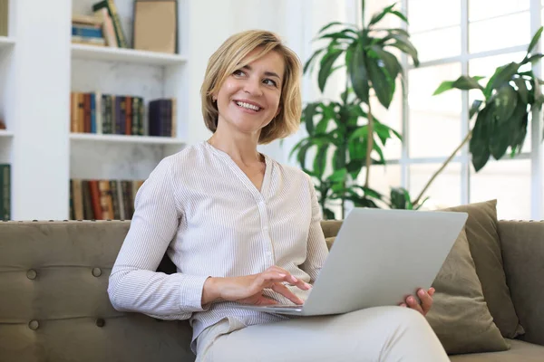 Glada Medelålders Kvinna Som Använder Laptop När Sitter Soffan Hemma — Stockfoto