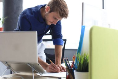 Ofisinde tasarım üzerinde çalışan yakışıklı bir erkek mimarın fotoğrafı.