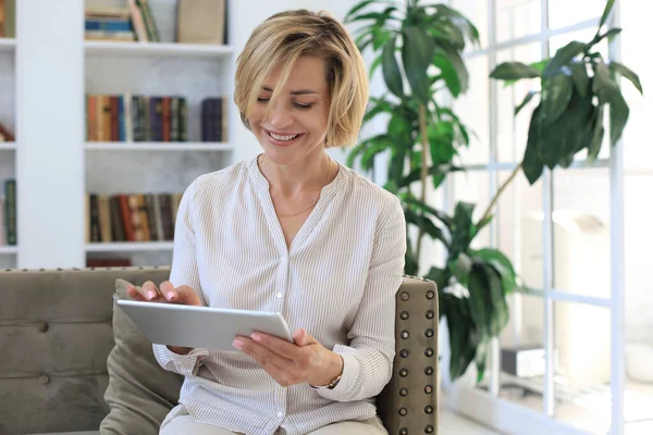 Mujer Alegre Mediana Edad Sentada Sofá Usando Aplicaciones Tabletas Computadora —  Fotos de Stock