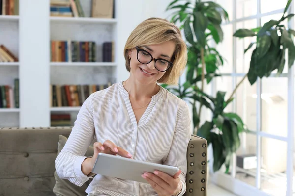 Glada Medelålders Kvinna Sitter Soffan Med Hjälp Dator Tablet Apps — Stockfoto