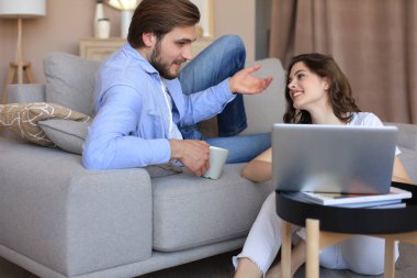 Mutlu çift oturuyor, oturma odasında dinleniyor, birlikte online alışveriş yapmak için dizüstü bilgisayar kullanıyorlar, film izliyorlar.