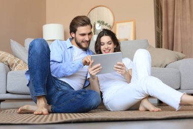 Yeni ev için tablet, yenileme ve iç tasarım ile evde oturan mutlu çift yeni ev dekorasyonu planlıyor..