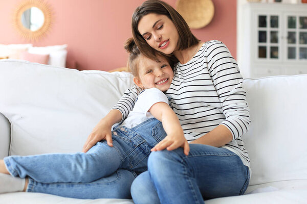 Счастливая любящая мама обнимает маленькую дочь, проводит время вместе дома