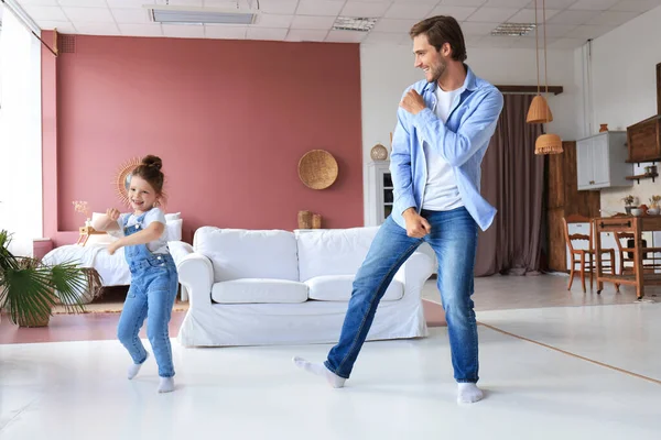 Handsome young man dancing at home with his little cute daugther