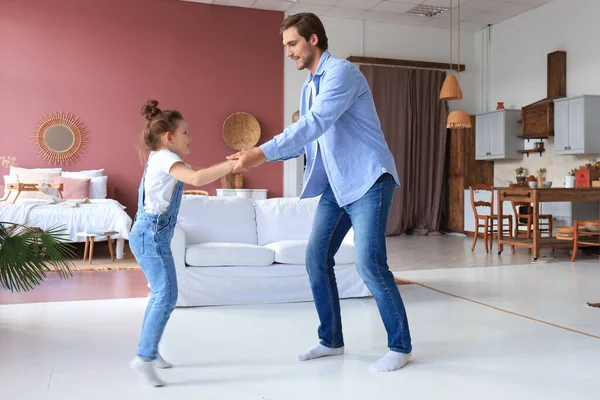 Handsome young man dancing at home with his little cute daugther