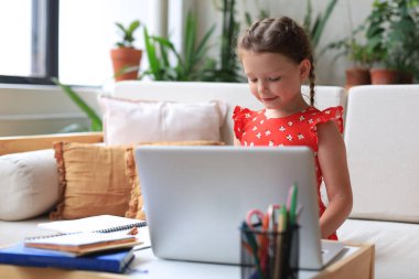 Mesafe öğrenme. Çevrimiçi e-öğrenme sisteminde çalışırken dizüstü bilgisayar kullanan neşeli küçük kız