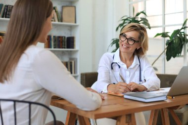 Ofisteki hastaya danışmanlık yapan orta yaşlı kadın doktor.