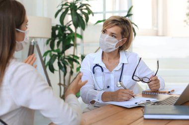 Ofisteki hastaya danışmanlık yapan orta yaşlı kadın doktor.