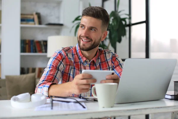 Aantrekkelijke Jongeman Die Thuis Aan Het Bureau Zit Mobiele Telefoon — Stockfoto