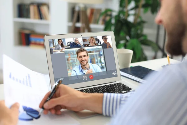 Empresario en auriculares hablando con sus colegas en videoconferencia. Equipo de negocios multiétnicos que trabajan desde casa usando el ordenador portátil, discutiendo el informe financiero de su empresa. —  Fotos de Stock