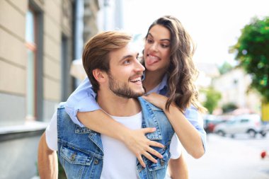 Yakışıklı genç bir adam dışarıda birlikte vakit geçirirken genç ve çekici bir kadını omuzlarında taşıyor.