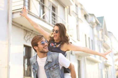 Yakışıklı genç bir adam dışarıda birlikte vakit geçirirken genç ve çekici bir kadını omuzlarında taşıyor.