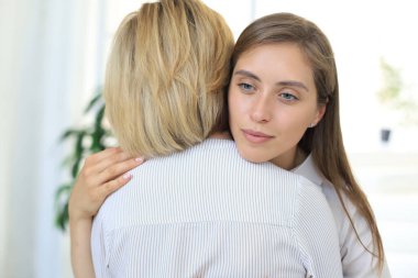 Endişeli orta yaşlı anne yetişkin kızına sarılıyor, endişelerini dinle.