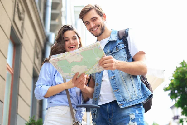 屋外に立っている間に地図と笑顔を保持する美しい若いカップル — ストック写真