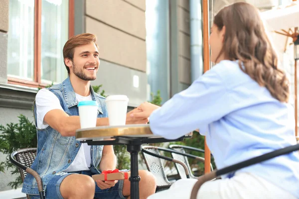 笑顔若いです女の子持っています日付とともに彼女のボーイフレンドとともにザコーヒーショップ 男保持現在のボックス — ストック写真