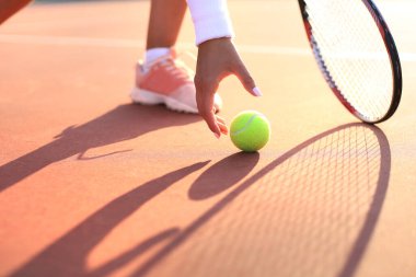 Tenisçi maç boyunca kil sahadan tenis topu kaldırır.