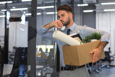 Üzgün işçi ofis malzemelerini yanında götürüyor.