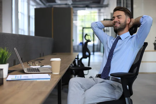 Mladý Moderní Obchodník Drží Ruce Hlavou Usmívá Zatímco Sedí Kanceláři — Stock fotografie