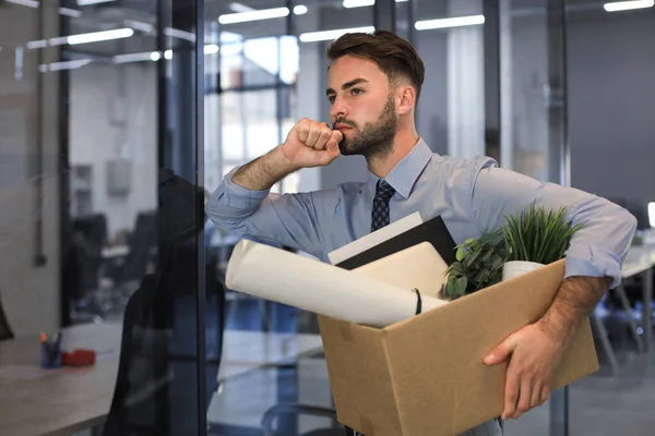 Sad dismissed worker is taking his office supplies with him from office