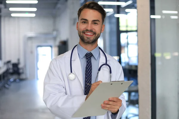 Hastane Koridorunda Yakışıklı Genç Doktor Kameraya Bakıyor Gülümsüyor — Stok fotoğraf