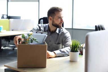Üzgün işçi ofis malzemelerini yanında götürüyor.