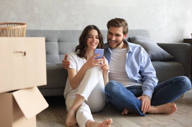 Mutlu çift yeni ev dekorasyonunu ve taşınma günü akıllı telefonu ile yeni ev dekorasyonunu planlıyorlar..