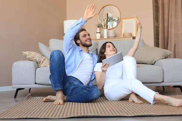 Yeni ev için tablet, yenileme ve iç tasarım ile evde oturan mutlu çift yeni ev dekorasyonu planlıyor..