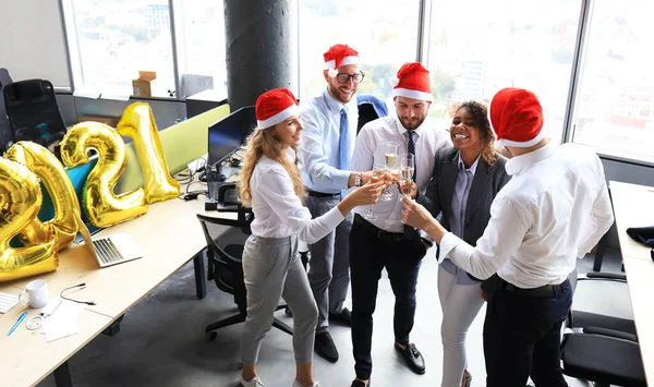 Pessoas de negócios estão comemorando férias no escritório moderno bebendo champanhe e se divertindo em co-working. Feliz Natal e Feliz Ano Novo 2021. — Fotografia de Stock