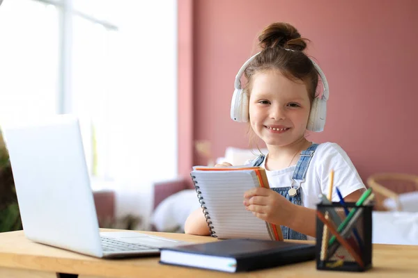 Niña Con Auriculares Sentada Escritorio Escribiendo Cuaderno Estudiando Línea Hacer Imagen de archivo