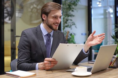 Gülümseyen genç iş adamı ofiste video görüşmesi yapıyor.