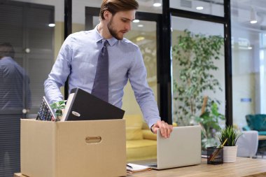 Üzgün işçi ofis malzemelerini yanında götürüyor.