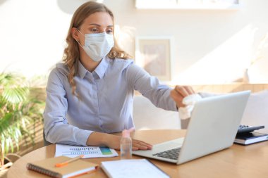 Kadın dezenfektan jel kullanıyor. Bilgisayarı dezenfektanla temizliyorum. Coronavirus koruması