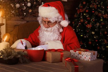 Mutlu Noel Baba 'nın portresi Noel ağacının yanındaki odasında oturuyor ve Noel mektuplarına cevap veriyor.