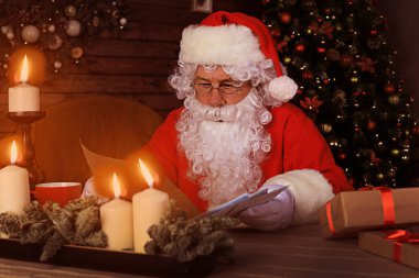 Mutlu Noel Baba 'nın portresi Noel ağacının yanındaki odasında oturuyor ve Noel mektubu ya da dilek listesi okuyor.