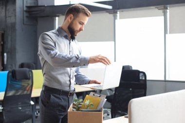 Üzgün işçi ofis malzemelerini yanında götürüyor.