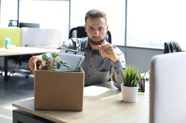 Üzgün işçi ofis malzemelerini yanında götürüyor.