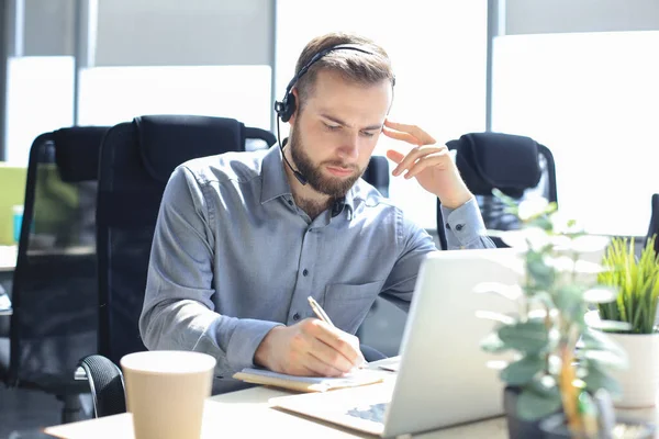 Uśmiechnięty Operator Call Center Słuchawkami Siedzącymi Nowoczesnym Biurze Przeglądający Informacje — Zdjęcie stockowe