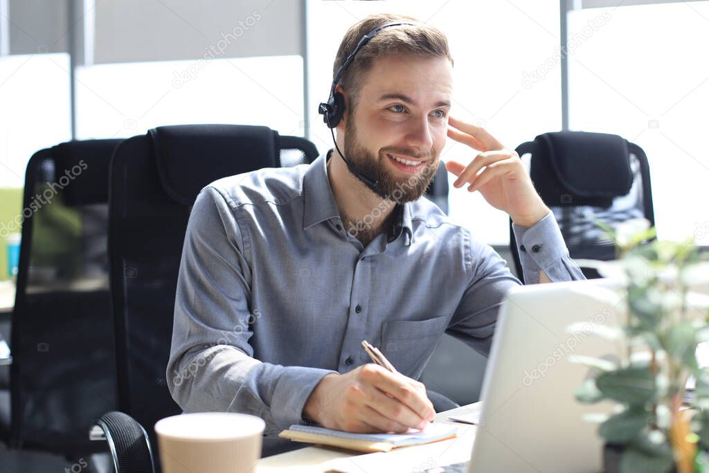 Smiling male business consultant with headphones sitting at modern office, video call looking at laptop screen. Man customer service support agent helpline talking online chat