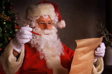 Mutlu Noel Baba 'nın portresi Noel ağacının yanındaki odasında oturuyor ve Noel mektubu ya da dilek listesi okuyor.