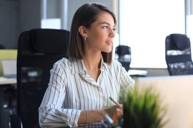 Güzel iş kadını büro masasında otururken bir şeyler yazıyor..