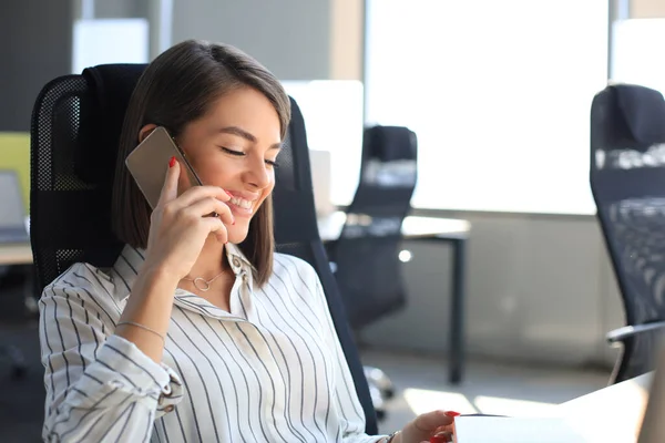 Atraktivní Obchodní Žena Mluvit Kolegy Mobilním Telefonu Zatímco Sedí Kanceláři — Stock fotografie