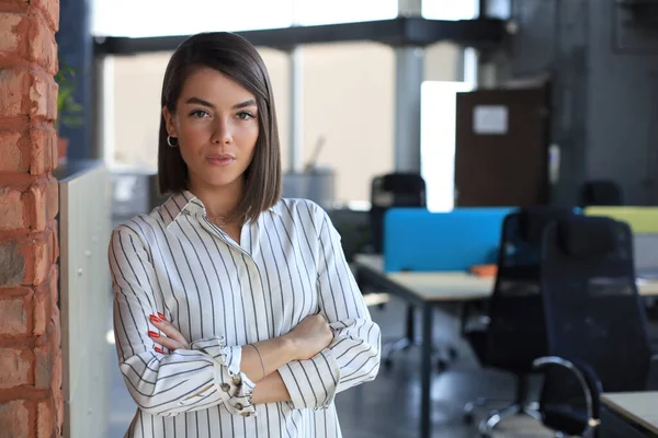 Attractive business woman looking at camera while standing in the office