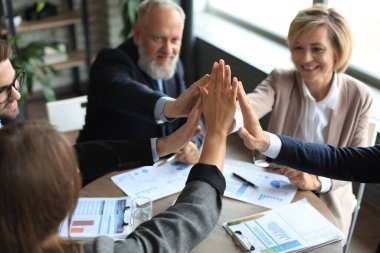 Ofiste oturan mutlu insanlar iş arkadaşlarına beşlik çakıyor.