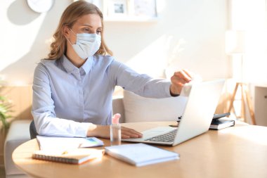 Kadın dezenfektan jel kullanıyor. Bilgisayarı dezenfektanla temizliyorum. Coronavirus koruması