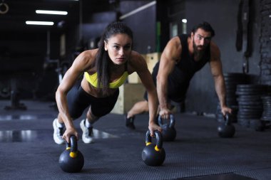 Spor salonunda şınav çeken kadın ve erkek.